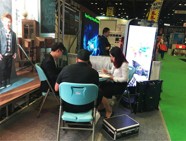 奥兰多橘城会展中心星空游戏展位现场，外贸部经理黄勇强和何巧玲与意向客户在交谈中